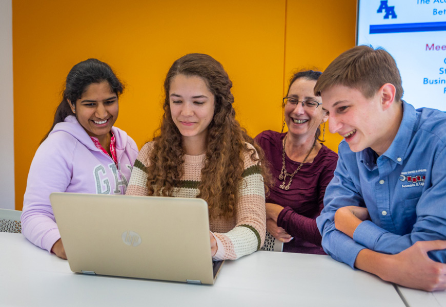 Students working together on their final project with a staff member