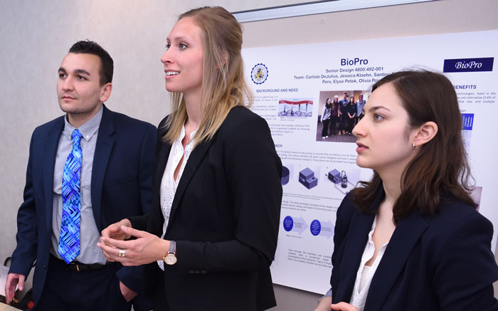 Three students with a poster making a presentation at The University of Akron Interdisciplinary Symposium