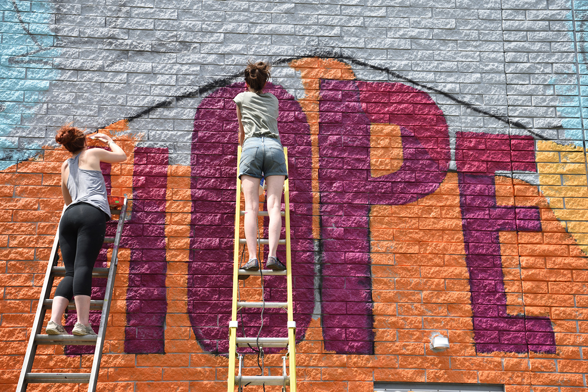 Students painting a outside wall in the city of akron