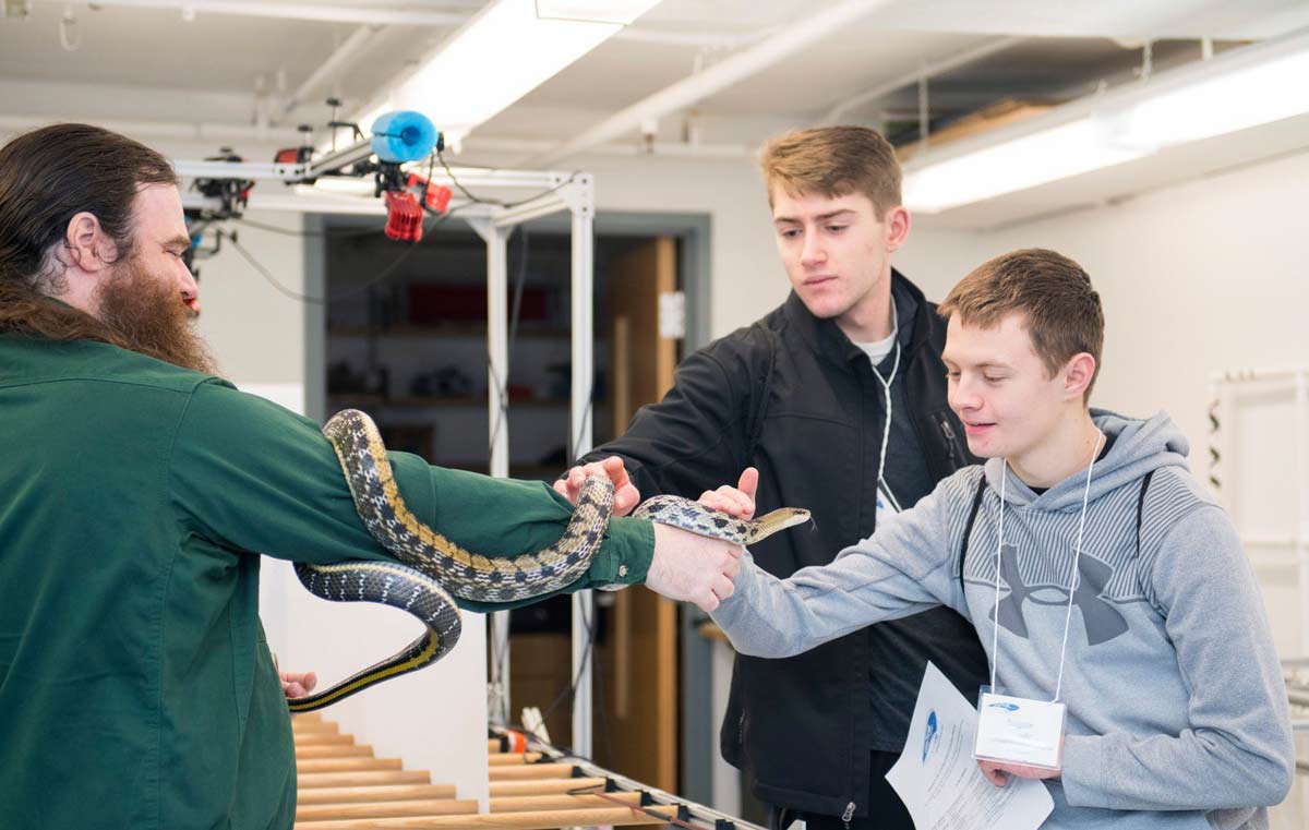 Professor Dr. Henry Astley shows two students a snake in a lab