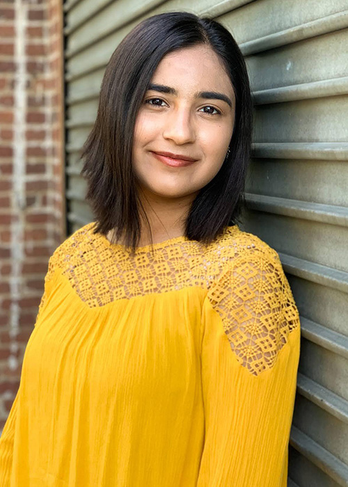 Headshot of girl with black hair and in yellow top.