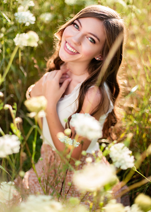 Headshot of girl in white dress outside.