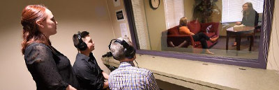 UA professor and PhD students observe a counseling session through a two-way mirror at the School of Counseling clinic.